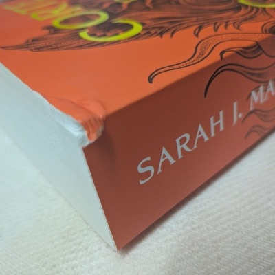 Canto de livro com capa laranja e texto SARAH J. MAAS