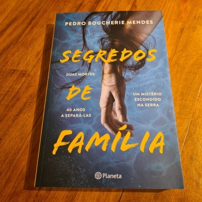 Capa do livro 'Segredos de Família' com imagem de mão sobre água e texto em amarelo e branco