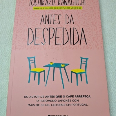 Capa de livro rosa com texto e ilustração de mesa azul com duas cadeiras e chávenas amarelas