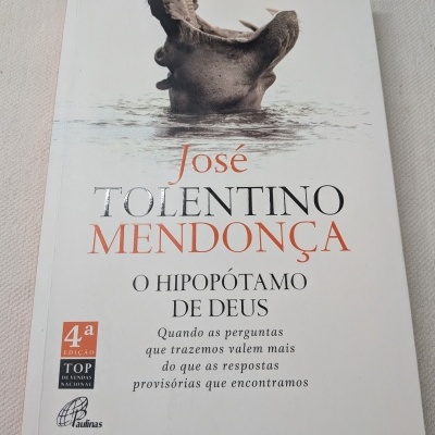 Capa de livro com a imagem de um hipopótamo a bocejar na água e texto impresso