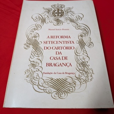Capa de livro branco com ornamento dourado e texto vermelho em fundo vermelho
