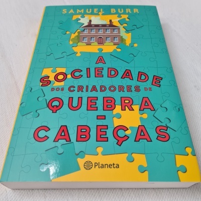 Capa de livro com título sobre quebra-cabeças e imagem de casa formada por peças de puzzle