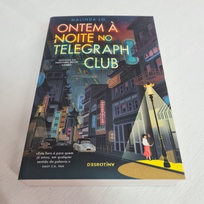 Capa de livro ilustrada com rua urbana à noite e casal junto a poste de luz.