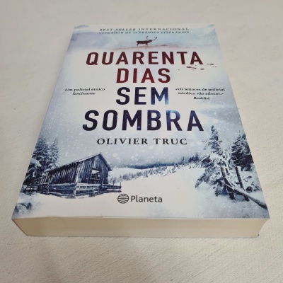Capa do livro 'Quarenta Dias Sem Sombra' sobre paisagem nevada com chalé de madeira.