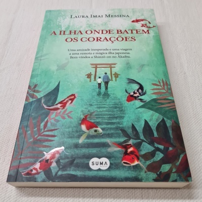 Capa de livro com ilustrações de carpas, duas pessoas e um torii, fundo verde água.