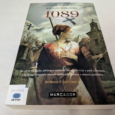 Capa de livro '1089' de Emílio Miranda com pessoas vestidas à moda antiga e igreja ao fundo