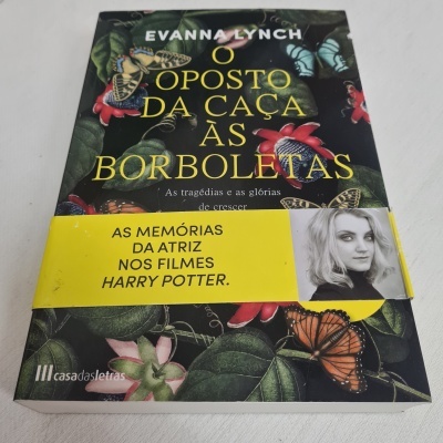 Livro com capa preta, borboletas e faixa amarela com texto e foto da autora