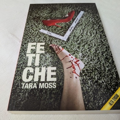 Capa do livro CETI CHE com texto, pé sangrando e sapato vermelho sobre relva