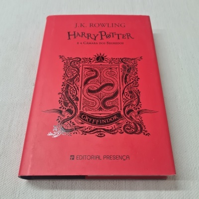 Livro Harry Potter e a Câmara dos Segredos com capa vermelha e brasão Gryffindor