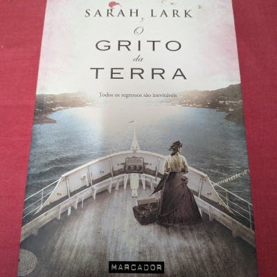 Capa de livro com mulher em navio e texto O Grito da Terra de Sarah Lark