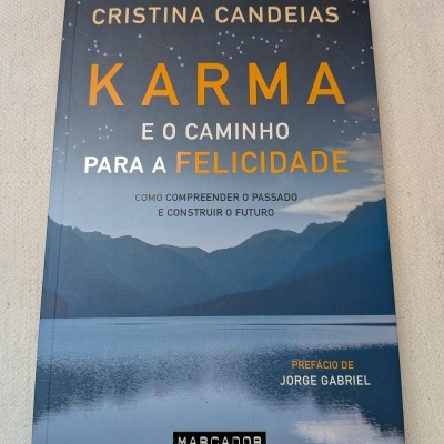Livro KARMA E O CAMINHO PARA A FELICIDADE com paisagem de montanhas e lago na capa