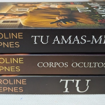 Três livros empilhados de Caroline Kepnes em tons castanho, preto e dourado