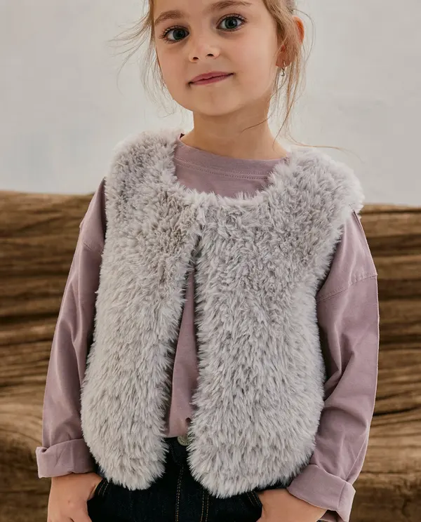 Criança com colete felpudo cinzento claro sobre camisa lavanda