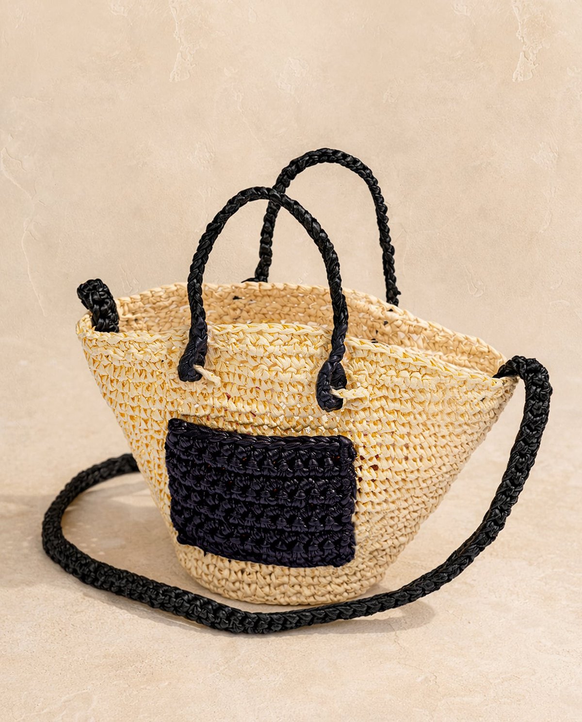 Mala tipo cesta em palha bege com alças e bolso frontal trançado preto