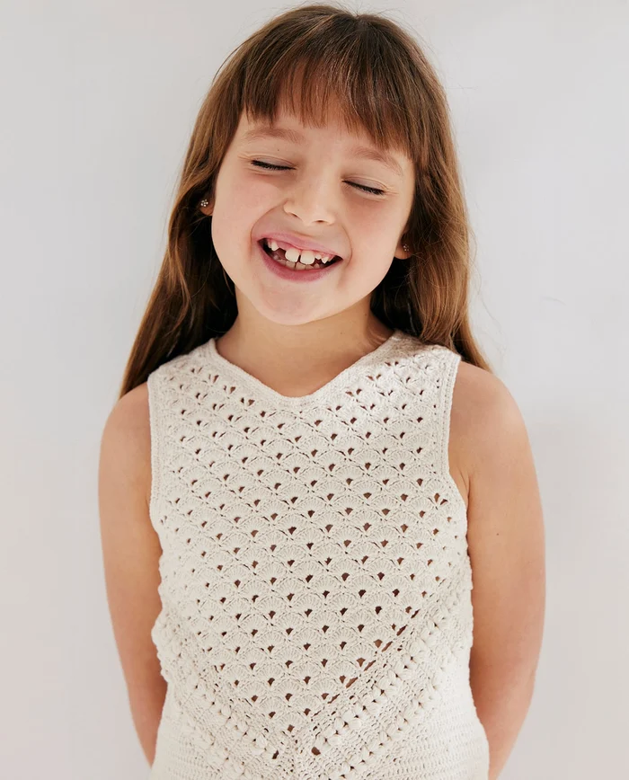 Menina sorridente a usar camisola branca de malha com padrão calado