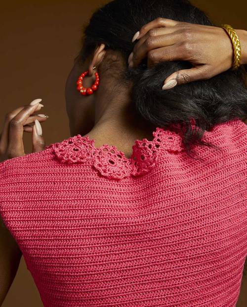 Peça de roupa rosa de malha com gola rendada, vista traseira.