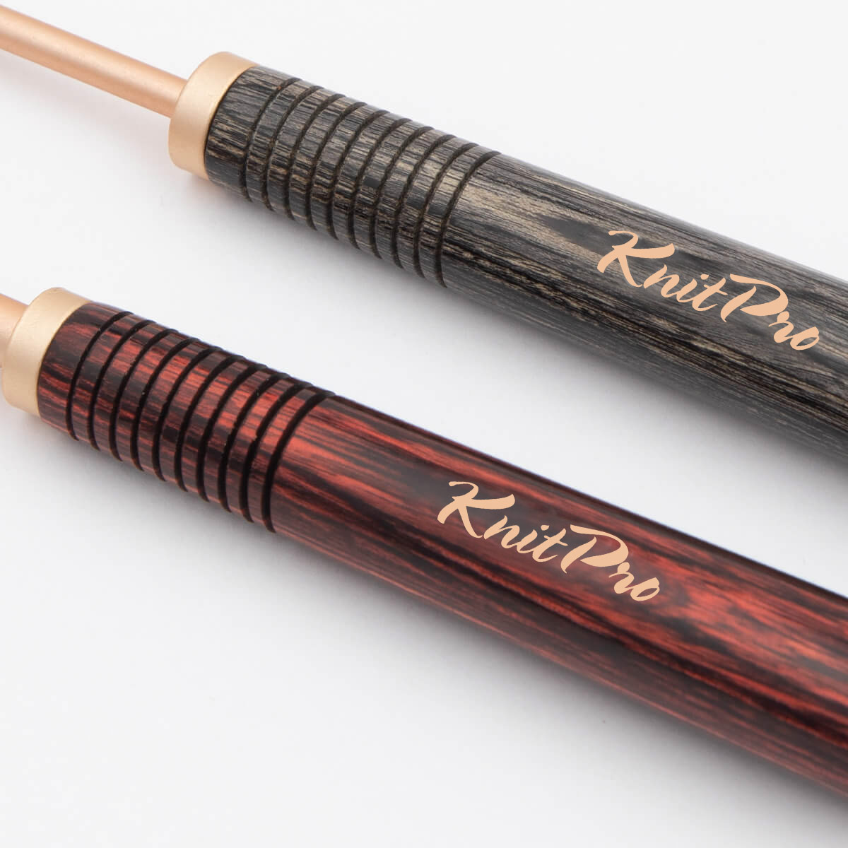 Duas agulhas de tricô com cabos de madeira texturizados em preto e vermelho escuro com inscrição KnitPro