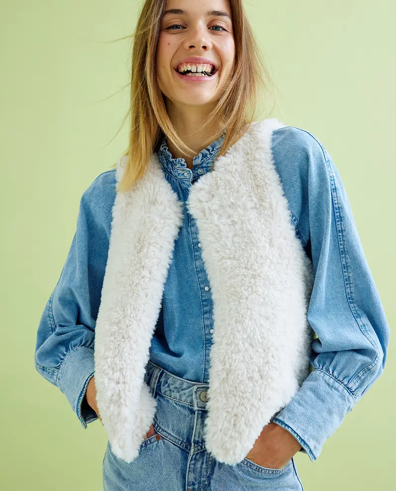 Colete feminino branco felpudo sobre camisa jeans azul