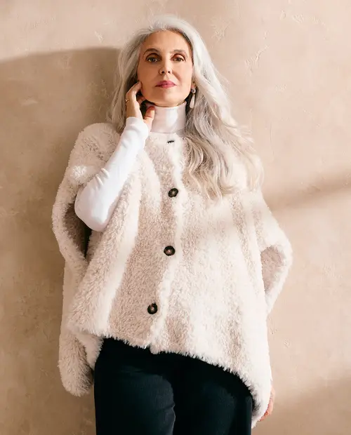 Mulher com casaco poncho de pelo sintético bege claro e blusa branca