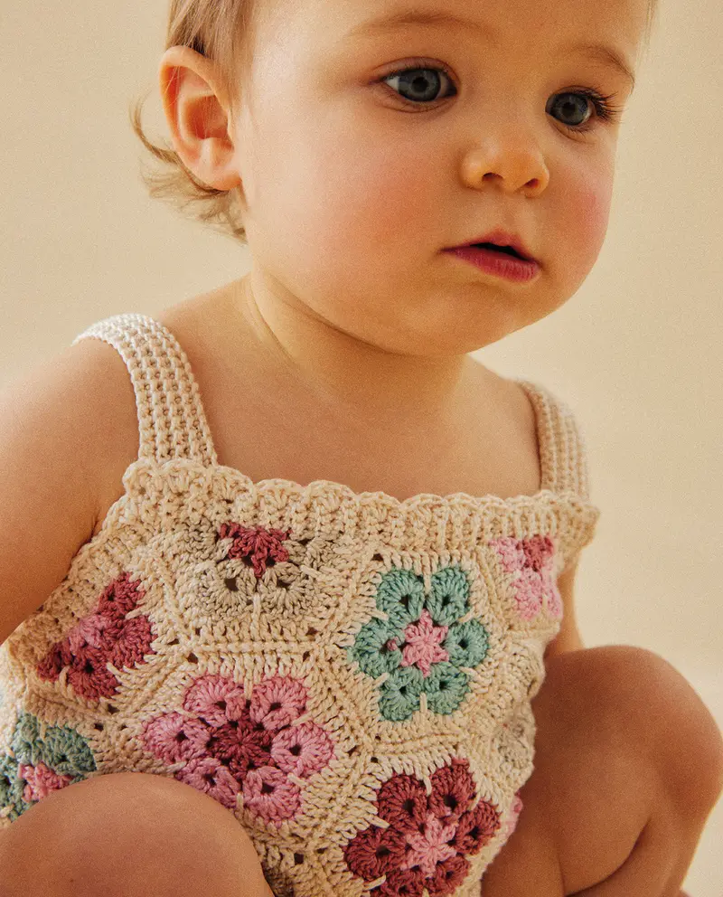 Top de crochet bege com flores rosas e verdes usado por criança