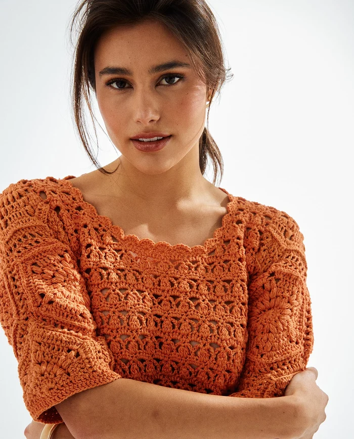 Blusa de malha crochetada cor de ferrugem com padrão detalhado e pontas onduladas na gola