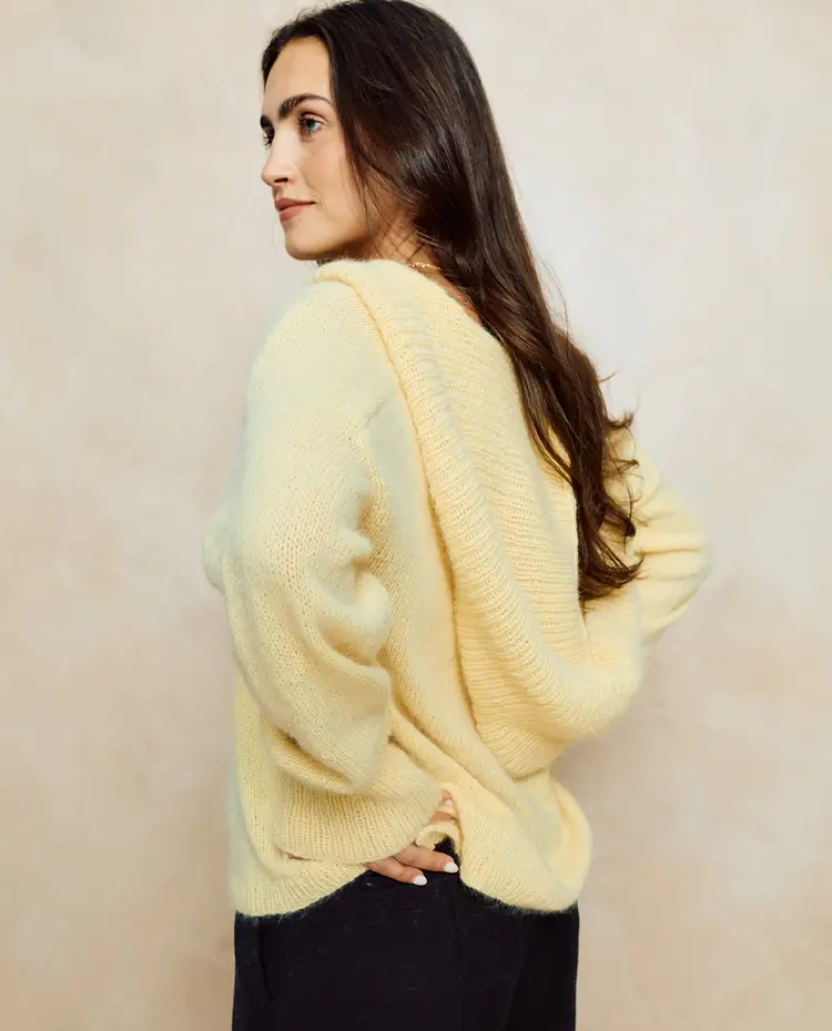Suéter amarelo claro de malha com capuz visto de perfil