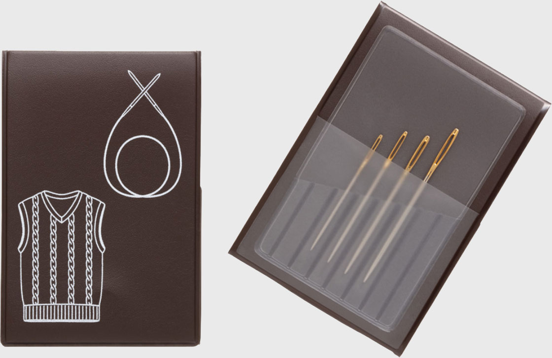 Conjunto de agulhas de costura em estojo transparente e caixa castanha com ilustração de camisola