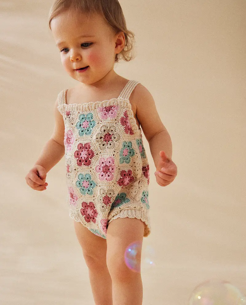 Macacão de bebé em croché com padrão floral colorido, usado por criança