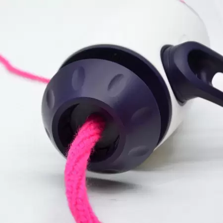 Objeto branco com ponta preta e corda rosa passando