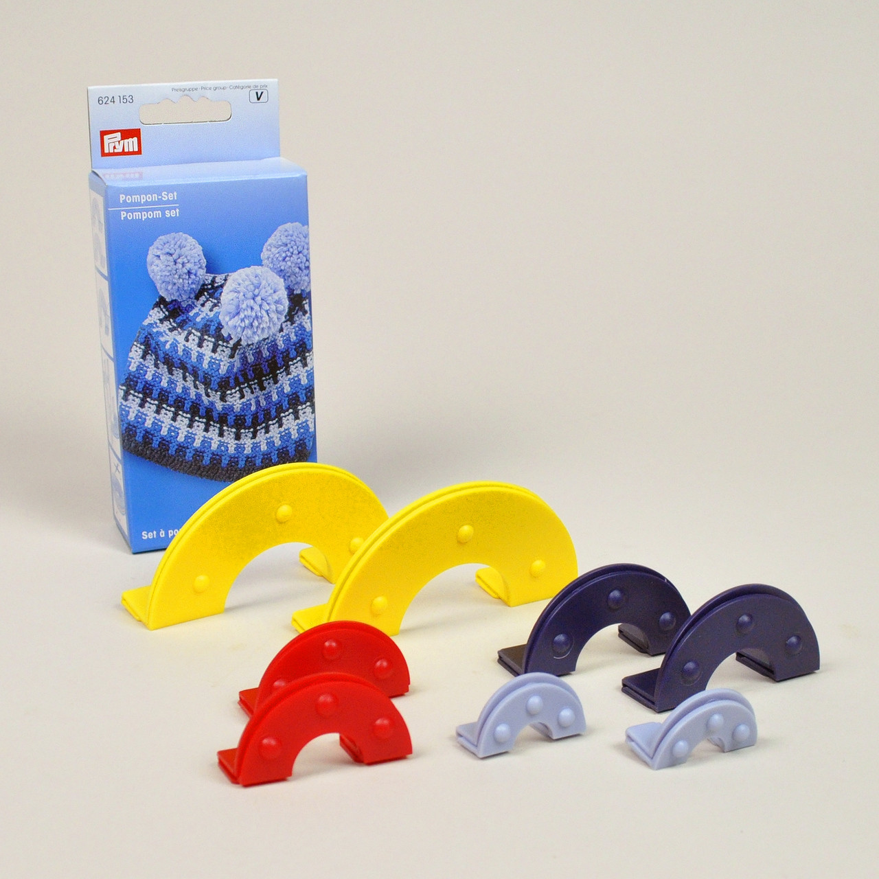 Conjunto de pompons Prym em plástico colorido com caixa azul e imagem de gorro com pompons