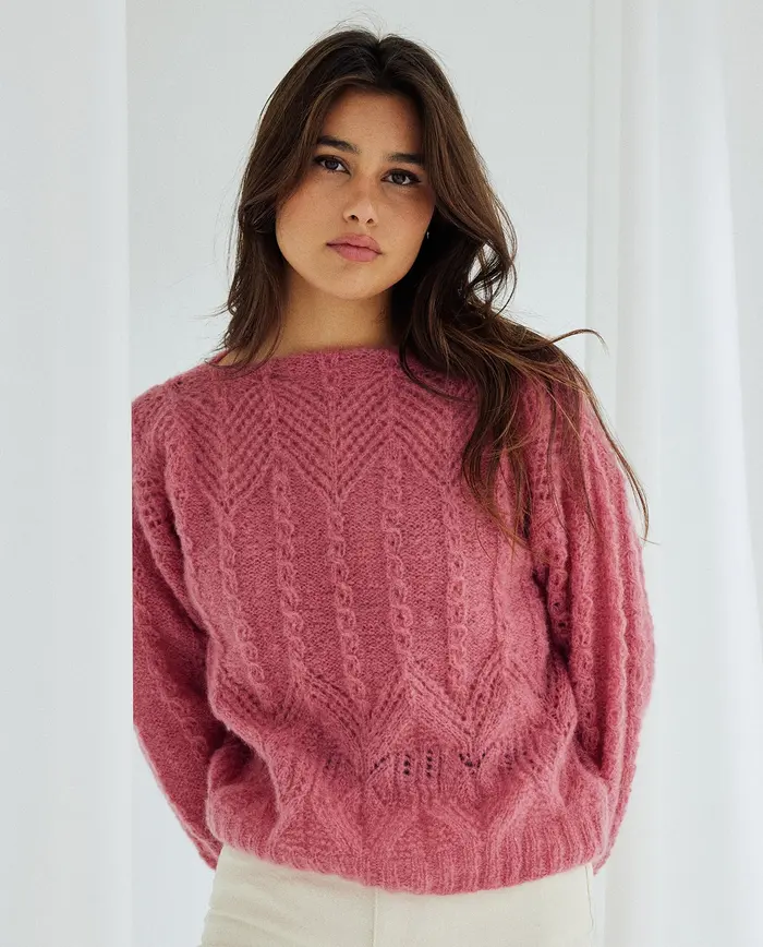 Mulher com camisola rosa de malha texturizada em ambiente claro