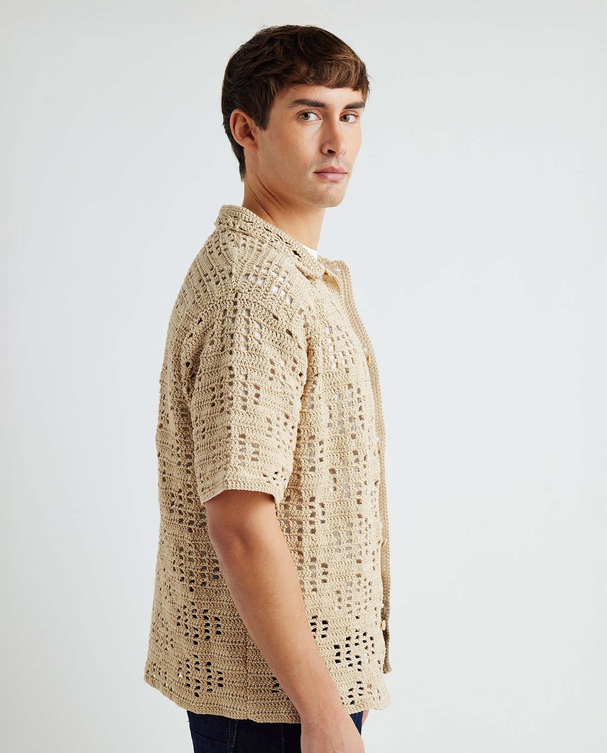 Camisa bege de malha com padrão aberto, vista lateral num modelo masculino