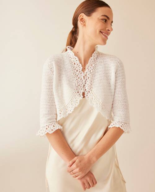 Mulher com bolero branco de croché e vestido creme