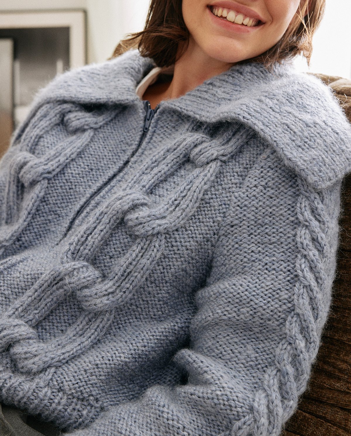 Casaco de malha azul claro com padrão de tranças grossas e fecho de correr central