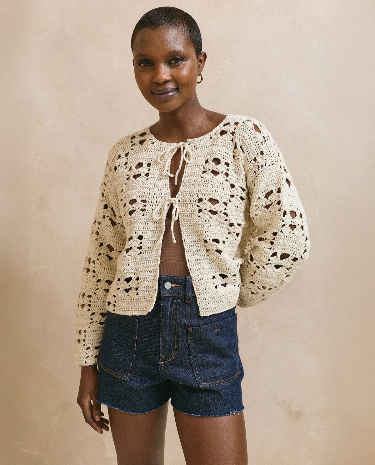 Camisola de malha creme com padrão de croché e calções de ganga azul escuro