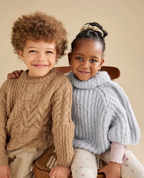 Crianças com camisolas de malha castanha e cinza sentadas juntas num banco