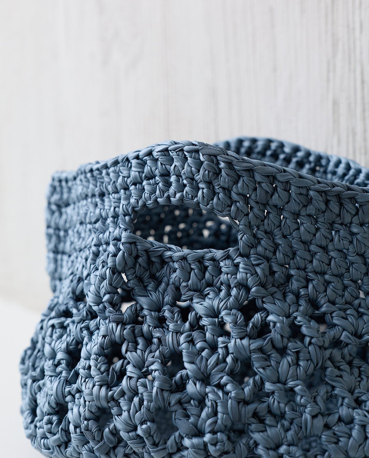 Cesto de malha azul com padrão trançado e alça retangular