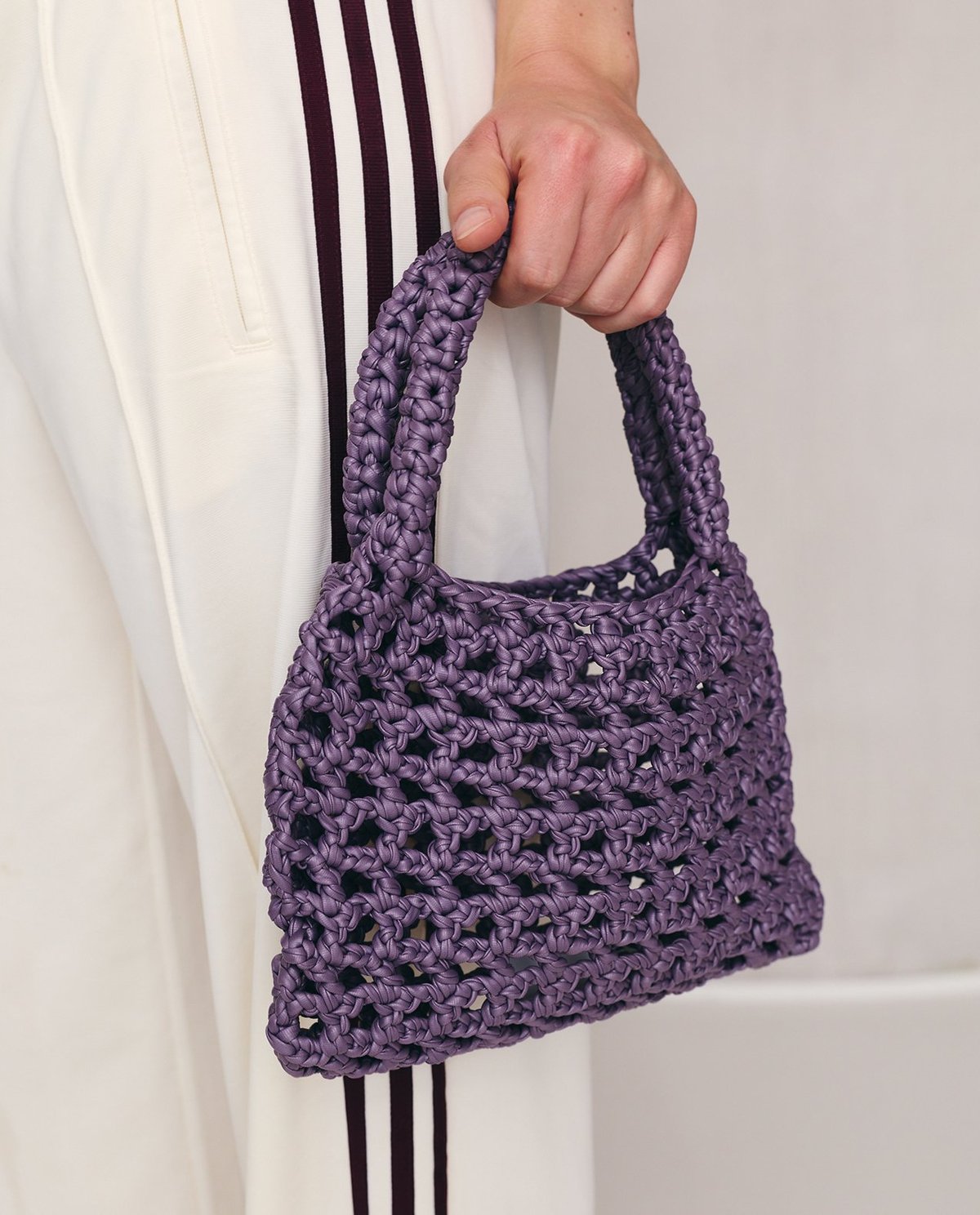 Bolsa pequena de crochê roxa com padrão aberto e alças grossas