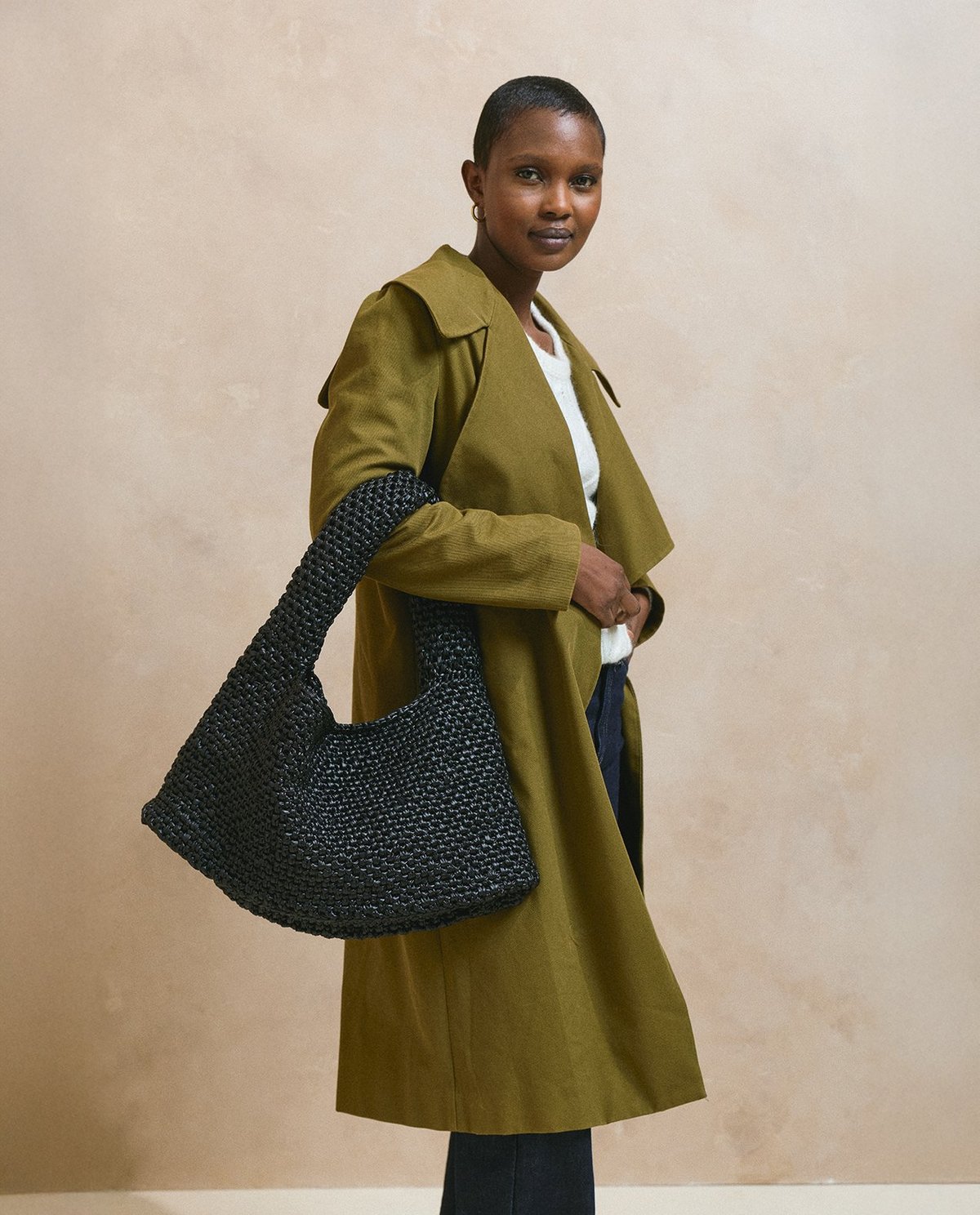 Mulher com saco preto de malha e casaco verde-oliva