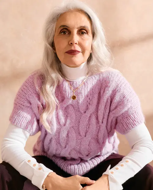 Mulher idosa com camisola rosa de malha e camisa branca de gola alta
