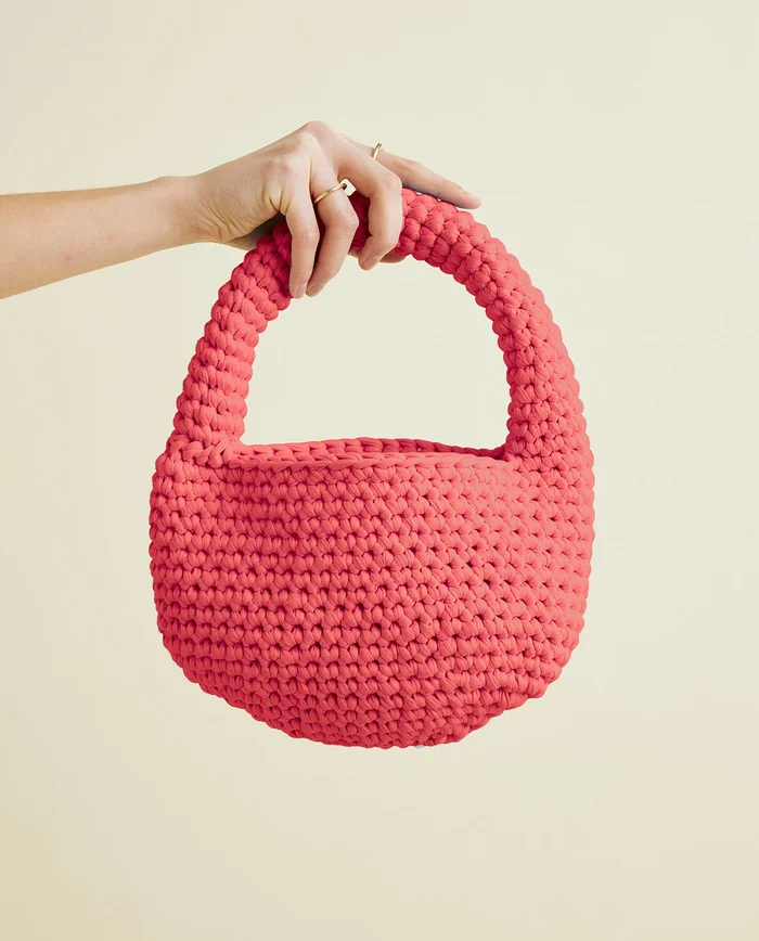Mala de mão de crochet cor de coral com pega espessa trançada