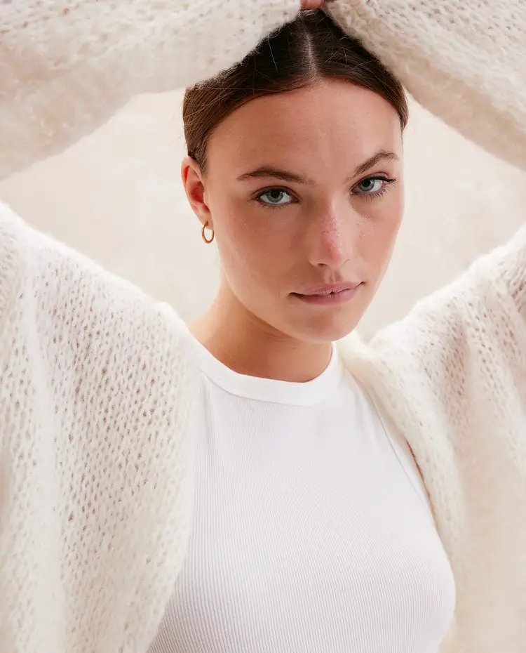 Mulher a usar camiseta branca de malha e cardigan branco felpudo