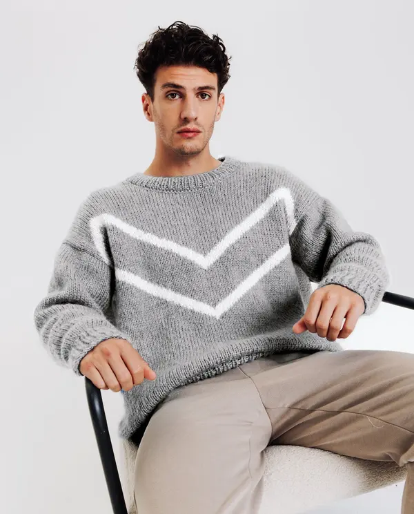 Homem com camisola de malha cinzenta com padrão branco sentado numa cadeira