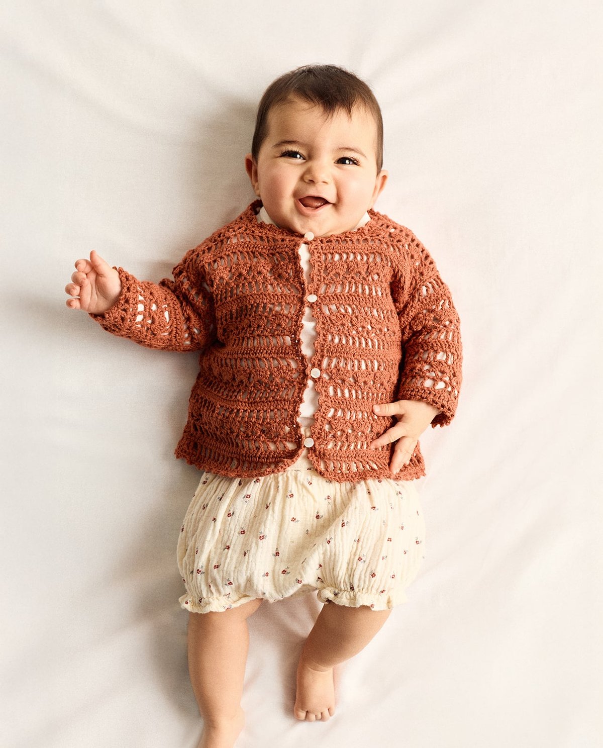 bebé com cardigã castanho e calção creme com flores pequenas