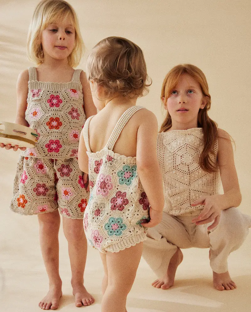 Crianças com roupas de crochê coloridas e bege em fundo neutro