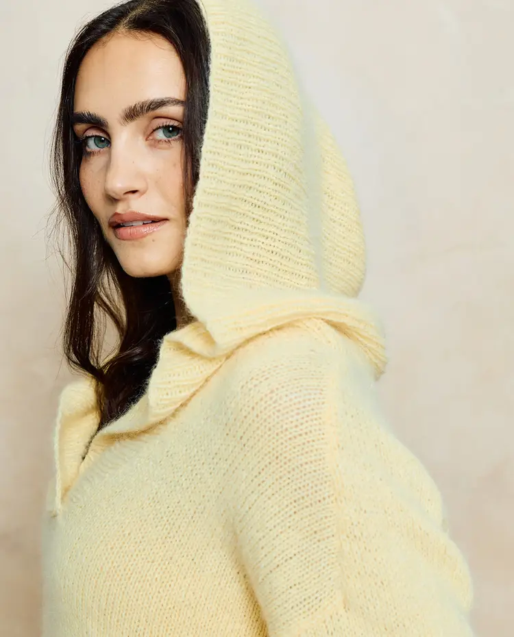 Mulher com camisola de malha amarela clara com capuz