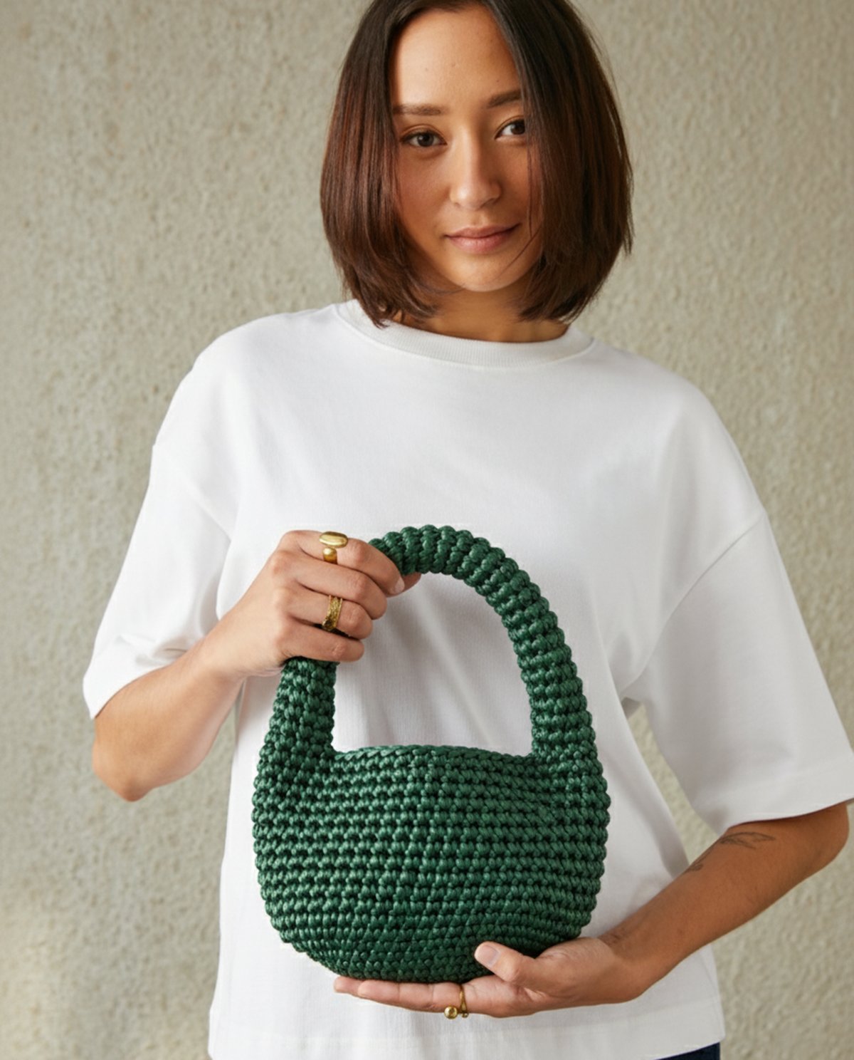 Mulher a segurar mala verde de mão trançada