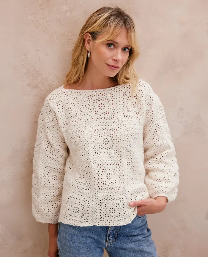 Mulher com camisola branca de malha crochetada e calças de ganga