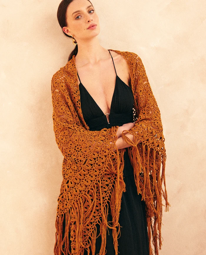 Mulher com vestido preto e xale de croché laranja com franjas longo