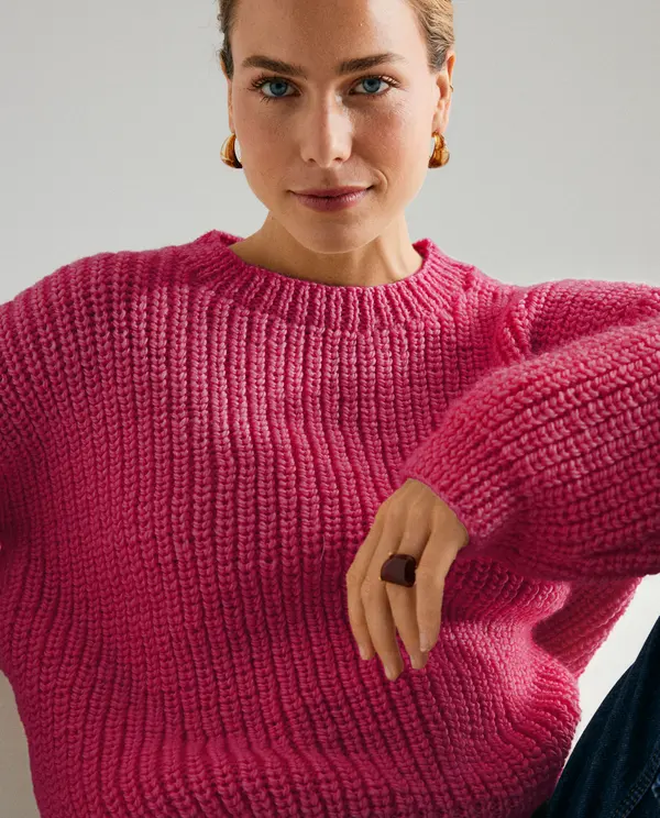 Mulher com suéter magenta de malha grossa e anel castanho